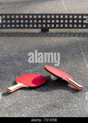 Deux raquettes de tennis de table allongé sur une table de ping-pong en béton. Aire de l'objet, la lumière du soleil. Active dans l'air libre. Banque D'Images