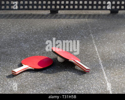 Deux raquettes de tennis de table allongé sur une table de ping-pong en béton. Aire de l'objet, la lumière du soleil. Active dans l'air libre. Banque D'Images