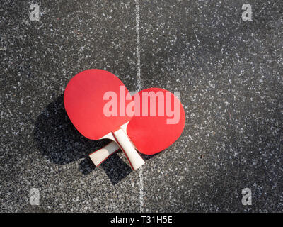 Deux raquettes de tennis de table allongé sur une table de ping-pong en béton. Aire de l'objet, la lumière du soleil. Active dans l'air libre. Banque D'Images