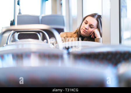 Triste femme fatiguée en train ou en bus. Un passager ennuyé ou mécontent assis dans le tramway s'est penché contre la main. Une dame contrariée dans un bus retardé. Banque D'Images