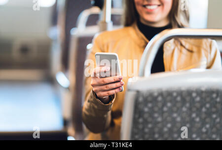 Femme souriante utilisant un smartphone en train, métro, bus ou tram. Texte Lady dans les transports en commun ou en utilisant la connexion wi-fi gratuite. Banque D'Images