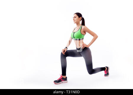 Une femme brune coach sportif dans une salle de sport et se jette par le leggings, pieds en avant, les mains sont tenues sur le côté sur un livre blanc isola Banque D'Images