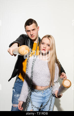 Jeux de sports. Close up fashion portrait de deux jeunes cool hipster girl and boy portant des jeans usés. La femme et l'homme avec un des bâtons de baseball. Studio shot of two cheerful meilleurs amis s'amusant et en faisant des visages. ludique Banque D'Images