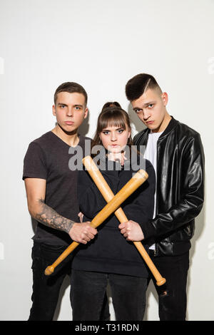 Jeux de sports. Close up fashion portrait de deux jeunes cool hipster girl and boy portant des jeans usés. La femme et l'homme avec un des bâtons de baseball. Studio shot of two cheerful meilleurs amis s'amusant et en faisant des visages. ludique Banque D'Images