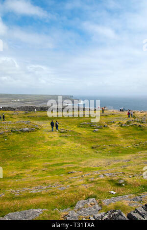 Les touristes à l'imposant Dun Aengus Fort en pierre, l'Inishmore, les îles d'Aran, au large de la côte ouest. Le fort est un preched sur 100 mètres balayés par le hi Banque D'Images