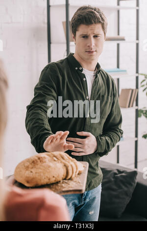 Portrait de femme tenant une planche à découper avec des tranches de pain près de bel homme avec l'intolérance au gluten Banque D'Images