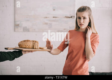 Portrait de l'homme tenue à découper avec des tranches de pain près triste femme blonde avec allergie au gluten Banque D'Images