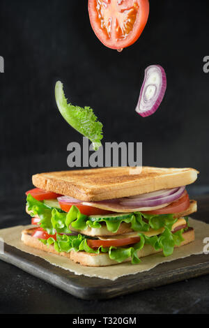 Voler des légumes pour sandwich, Salade de tomate, oignon, sur fond noir. Isolé Banque D'Images
