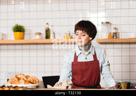 Belle, tatouée dans l'essuyage tablier Barista Bar comptoir avec rag Banque D'Images