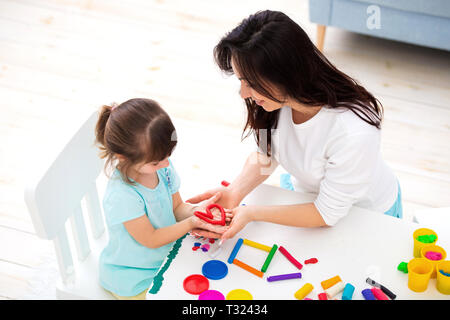 Mère et fille souriante sculpt coeur et nouvelle maison de plasticine. La créativité des enfants. Enfance heureuse. Rêves de pendaison. Banque D'Images