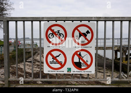 Rouge sur blanc panneau d'avertissement sur la clôture en acier galvanisé avec vue sur estuaire à marée basse dans le nord du Pays de Galles UK Banque D'Images