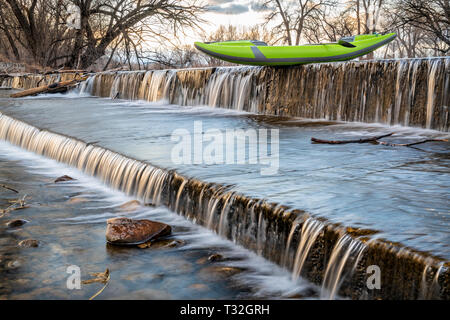 Whitewater Kayak gonflable avec une pagaie sur le dessus de barrage de dérivation de la rivière Powder - River à Fort Collins, Colorado dans un paysage au début du printemps Banque D'Images