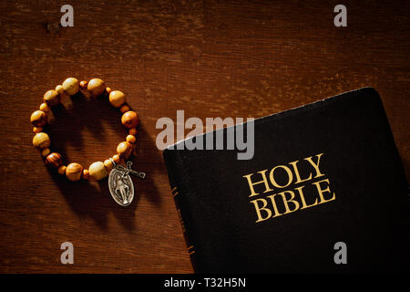 Sainte Bible et chapelet bracelet sur le bois dans une lumière chaude. Banque D'Images