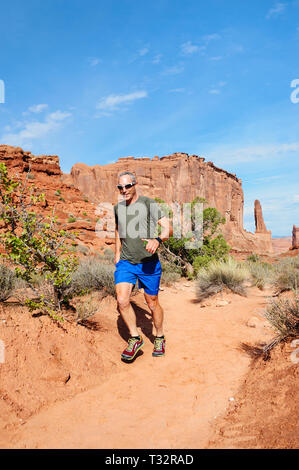 Man jogging avec téléphone dans sa main, l'avenue Park Trail, Arches National Park, Utah, USA. Banque D'Images