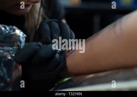 Femme artiste de tatouage en donnant un tatouage. Faire un tatouage Banque D'Images
