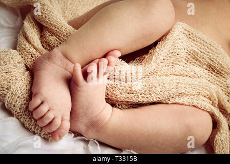 Un portrait Portrait d'un bébé nouveau-né, les orteils de pieds et jambes en swadded légèrement dans un environnement de couleur neutre Banque D'Images