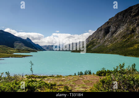 Vue imprenable sur le lac Gjende bleu cristal dans le parc national de Jotunheimen avec de belles montagnes derrière et au-dessus de ciel bleu Banque D'Images