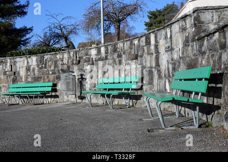 Bancs verts fait de bois et de béton photographié sur un jour de printemps ensoleillé à Nyon, Suisse. Sur cette photo, vous pouvez aussi voir allée asphaltée. Banque D'Images