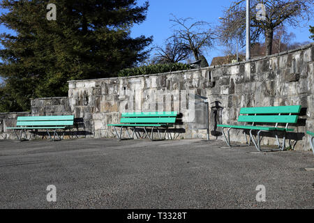 Bancs verts fait de bois et de béton photographié sur un jour de printemps ensoleillé à Nyon, Suisse. Sur cette photo, vous pouvez aussi voir allée asphaltée. Banque D'Images