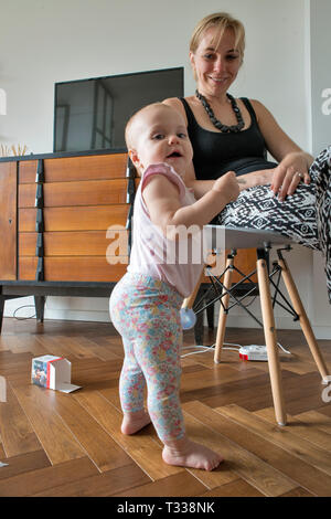 fille de 1 an apprenant à marcher, sa mère regarde Banque D'Images