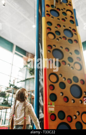 Petite fille regarde sur mur d'escalade, les enfants game center. Childs excités s'amuser sur l'aire de l'intérieur Banque D'Images