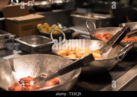 Restaurant Buffet avec trois casseroles de ami aliments, y compris les ailes de poulet, croquettes de poulet sur l'affichage, sous une lumière compteur Banque D'Images