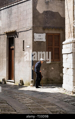 Scène de rue d'un homme âgé avec bâton de marche et sac shopping en cobble stones ruelle de Erice, Sicile, Italie Banque D'Images