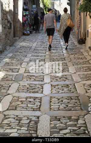 Scène de rue vue arrière de young couple in cobble stones ruelle de via Chiesamonte, Erice, Sicile, Italie Banque D'Images