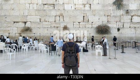 Retour d'un jeune touriste en vêtements décontractés et kippa sur la tête à la au mur des lamentations et religieux priant près du lieu sacré du judaïsme, J Banque D'Images