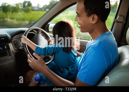 Enfant jouant avec le volant de papa Banque D'Images