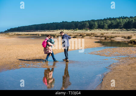 Une famille piscines d''eau croix laissées par la marée sur la plage de sable de Holkham bay, North Norfolk Coast, East Anglia, Angleterre, Royaume-Uni. Banque D'Images