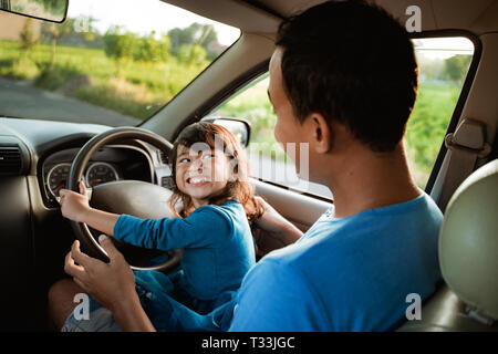 Enfant jouant avec le volant de papa Banque D'Images