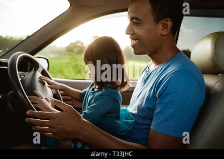 Enfant jouant avec le volant de papa Banque D'Images