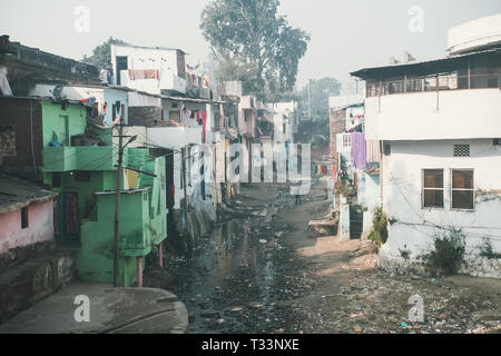 Un égout puant l'écoulement dans les bidonvilles. Quartier pauvre de Delhi, Inde. Chambre pauvres sur la colline en face d'une rivière sale de nos problèmes sociaux. Banque D'Images