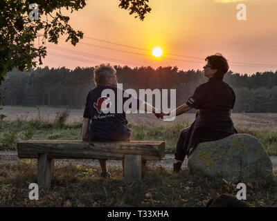 Deux femmes regardant un coucher de soleil dans la Lueneburger Heide près de Mechtersen, Niedersachsen, Allemagne. Banque D'Images