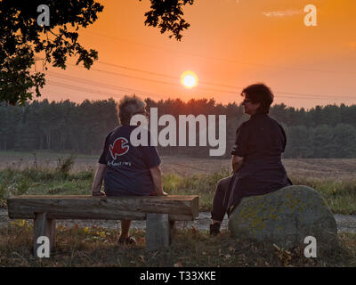 Deux femmes regardant un coucher de soleil dans la Lueneburger Heide près de Mechtersen, Niedersachsen, Allemagne. Banque D'Images