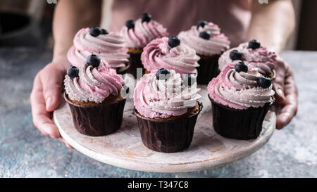 Femme pâtisserie mains tiennent un plat rond de délicieux muffins aux bleuets Banque D'Images
