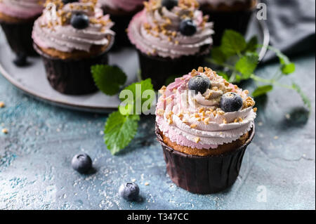 Petits gâteaux faits maison avec des bleuets sur fond de béton bleu foncé. Banque D'Images