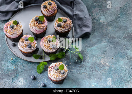 Petits gâteaux faits maison avec des bleuets sur fond de béton bleu foncé. Banque D'Images