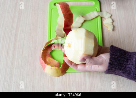 Pelés apple en main de la jeune fille. Pelure de pomme verte sur une planche à découper. Close up Banque D'Images