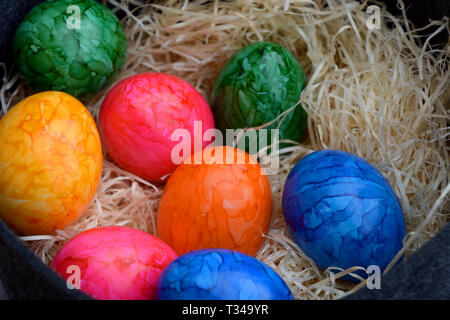 Panier de pâques rempli de paille de couleur blanche et les oeufs cuits, thème de Pâques avec les oeufs colorés, contexte heureux de Pâques Banque D'Images