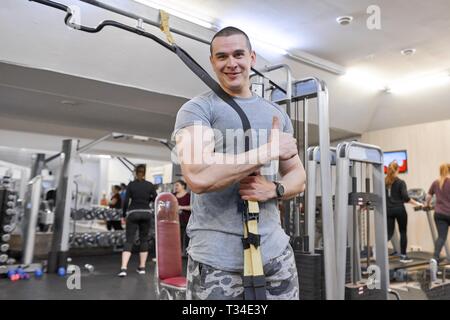 Portrait of young smiling smiling man musculaire forte en sport. Homme avec des sangles de remise en forme de boucles. Banque D'Images