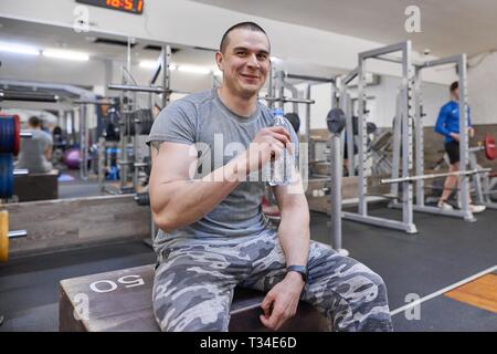 Jeune homme musclé solide dans l'eau potable à partir de la bouteille de sport. Banque D'Images