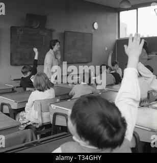 Années 1960, mains, plcture historique de jeunes enfants de l'école dans une classe de mettre leurs mains en réponse à une question de l'enseignant, England, UK. Banque D'Images