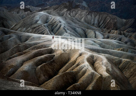 Femme marchant le long de la jante des Badlands, Death Valley, California, United States Banque D'Images