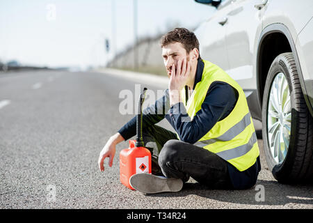 Homme avec désespoir émotions assis avec le plein de sa voiture près de la cartouche sur le bord de la route Banque D'Images