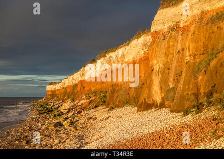 Hunstanton Cliffs au coucher du soleil avec un ciel d'orage, sur la côte de Norfolk, où les fonds de craie blanche calcaire rouge en une formation. Angleterre, Royaume-Uni. Banque D'Images