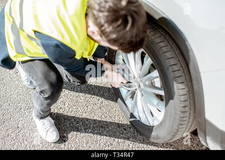 Gilet homme en dévissant la roue brisée sur le bord de la route Banque D'Images