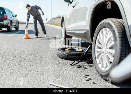 L'assistance routière d'urgence mettre travailleur près du cône sur l'autoroute voiture cassée Banque D'Images