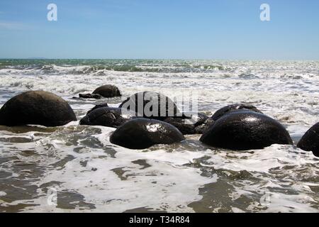 Close up de Moeraki Boulders sphérique de pélites sur la plage baignée par les vagues déferlantes de la mer, Koekohe plage, plage de galets, Nouvelle-Zélande Banque D'Images